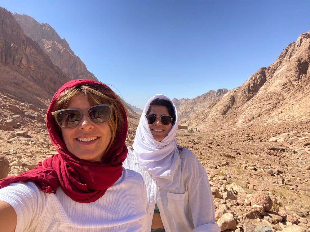 Dos viajeras con pañuelos sonriendo en el desierto
