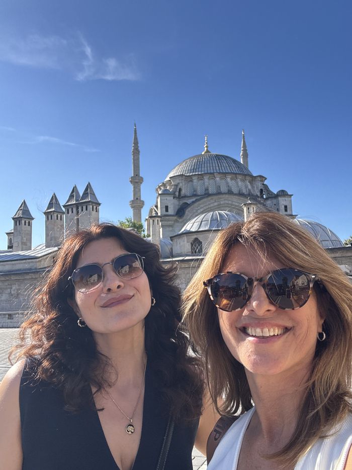 Dos viajeras sonriendo frente a la mezquita